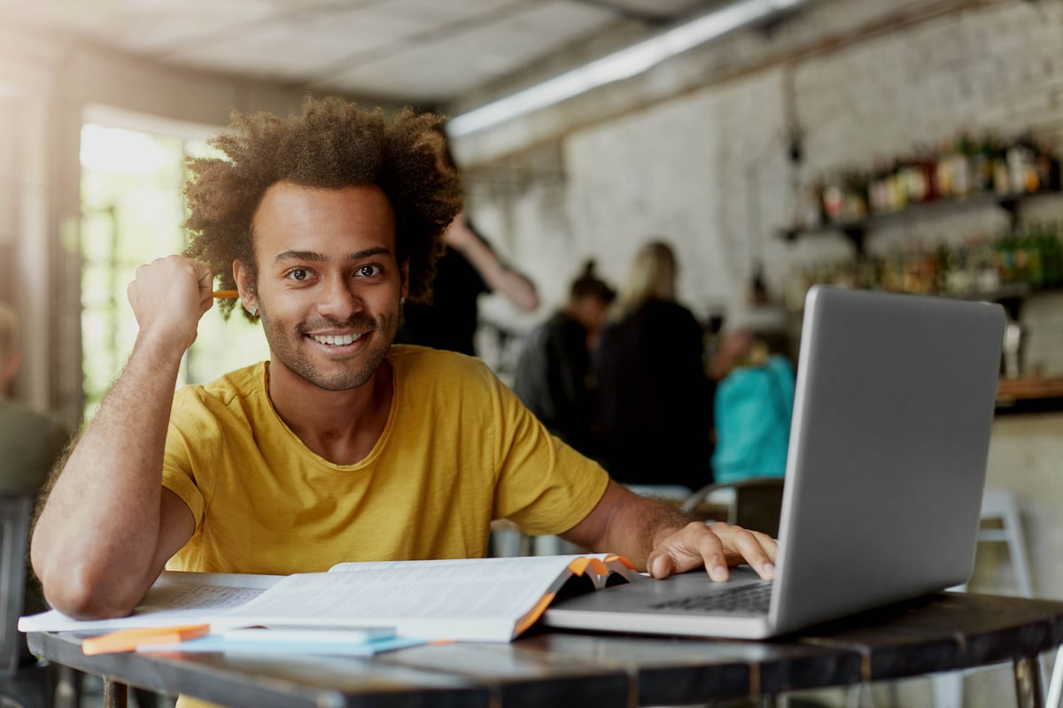 happy-positive-african-american-college-student-with-cheerful-cute-smile-using-wireless-internet-connection-laptop-computer-coffee-shop-while-looking-information-online-research-project